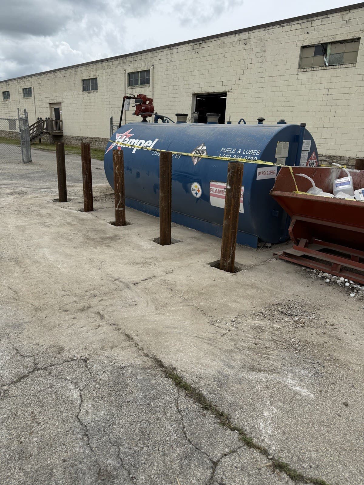 Steel bollards being set in concrete around a fuel tank