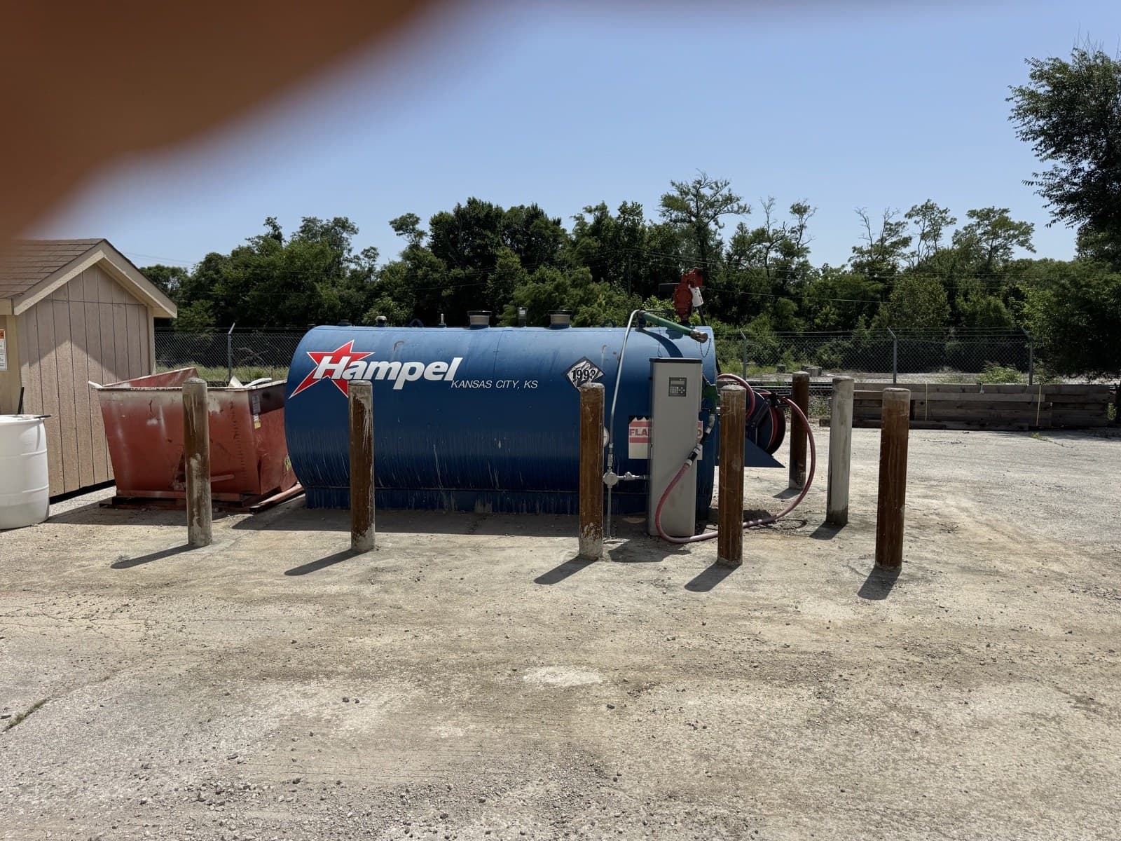 Completed row of protective steel bollards around a fuel tank